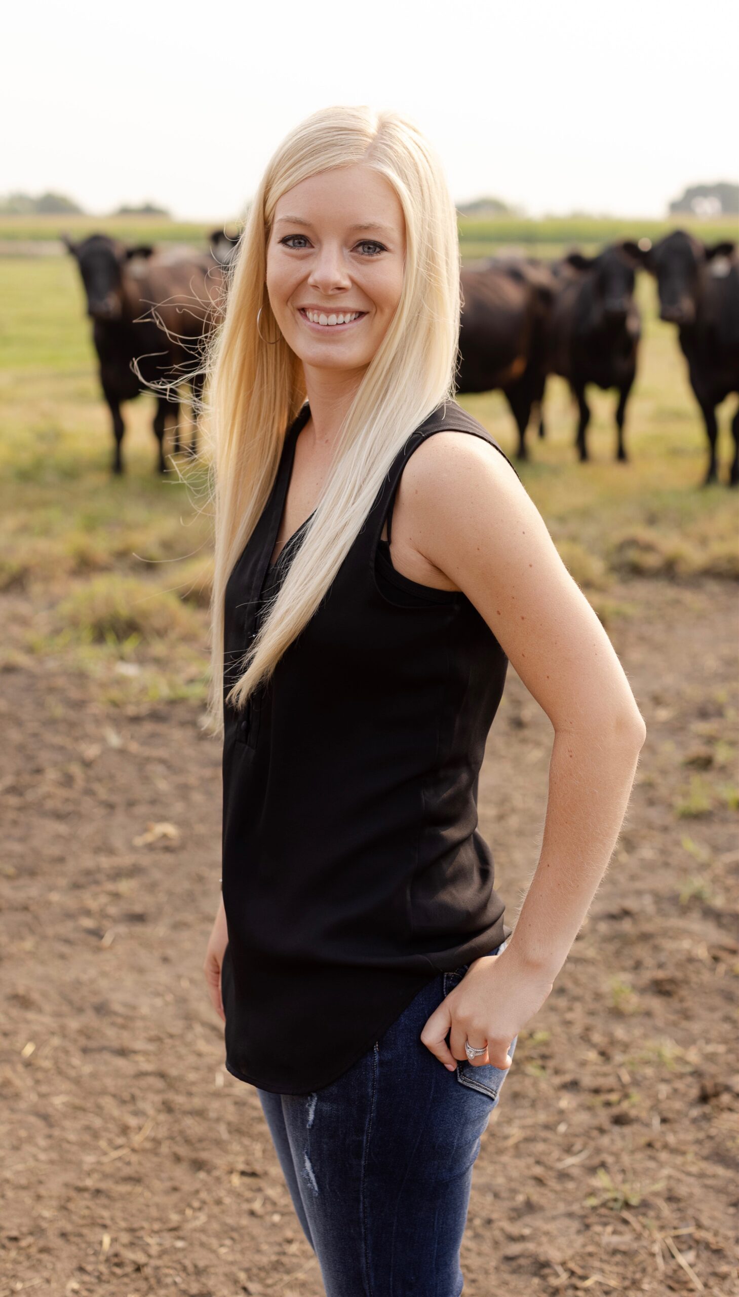 A woman standing in front of some cattle.
