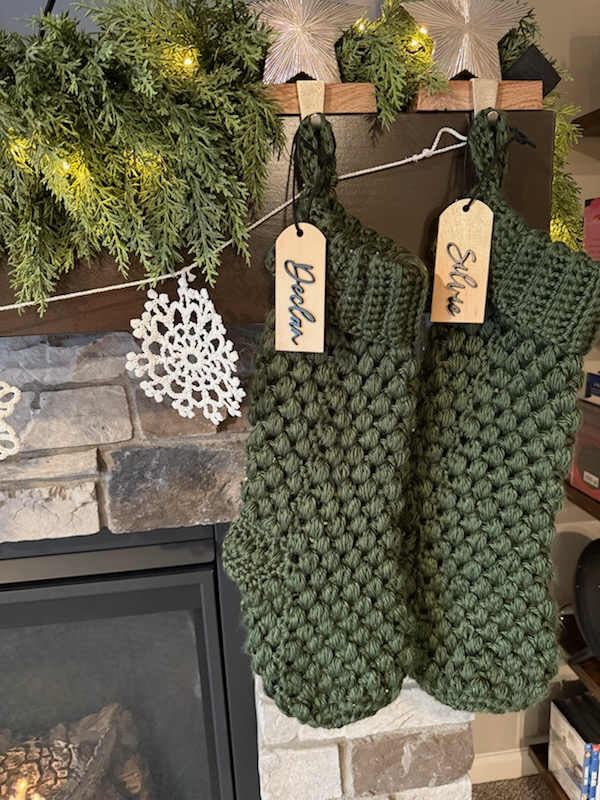 Two handmade stockings hang in front of a fireplace.