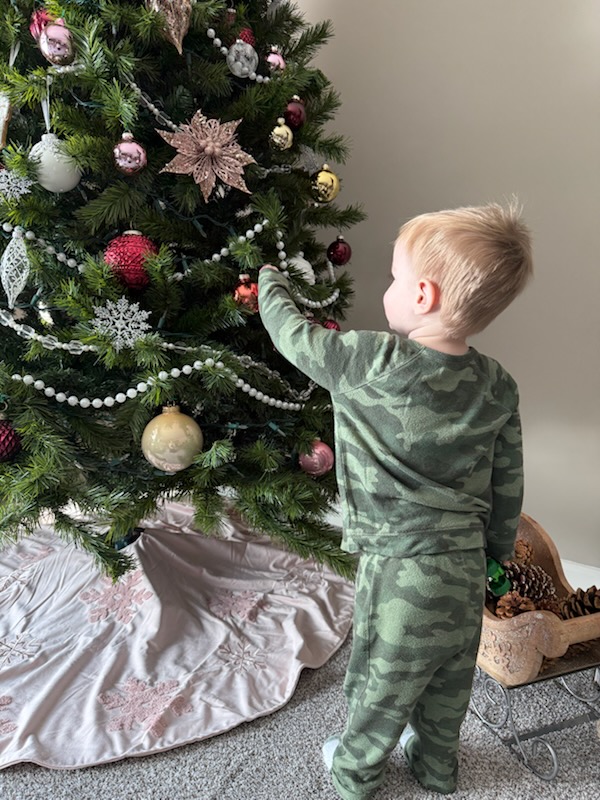 A young boy looks at a decorated Christmas tree.